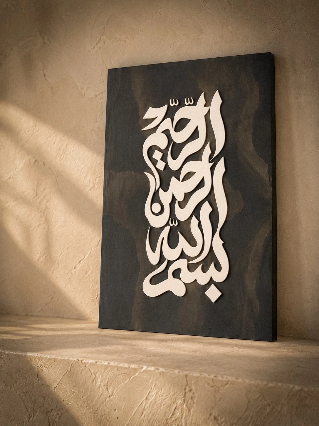 A hand-finished Bismillah plaque resting on a sunlit plaster shelf